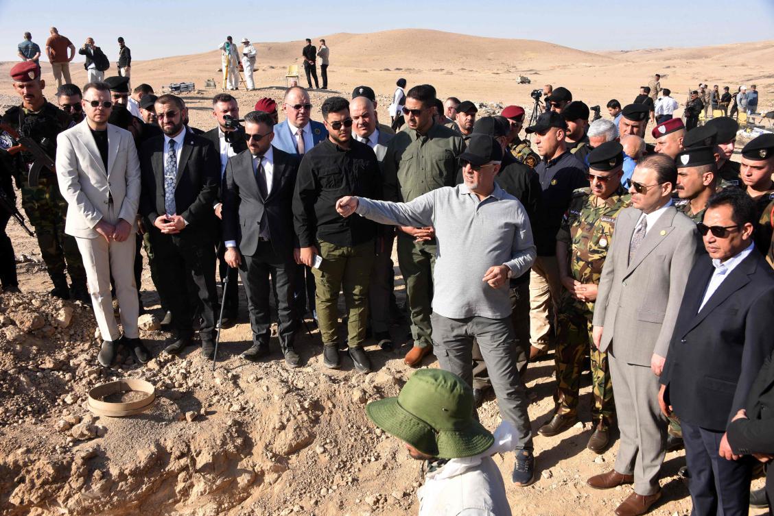 Iraqi authorities gather near a sinkhole at the Khasfa site near the northern city of Mosul, where they have begun excavating a mass grave believed to contain thousands of Daesh victims on Aug. 17, 2025. (AFP)