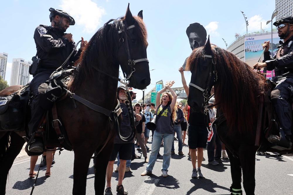A demonstrator shouts slogans in front of mounted policemen during an anti-government protest in Tel Aviv on Aug. 17, 2025. (AFP)