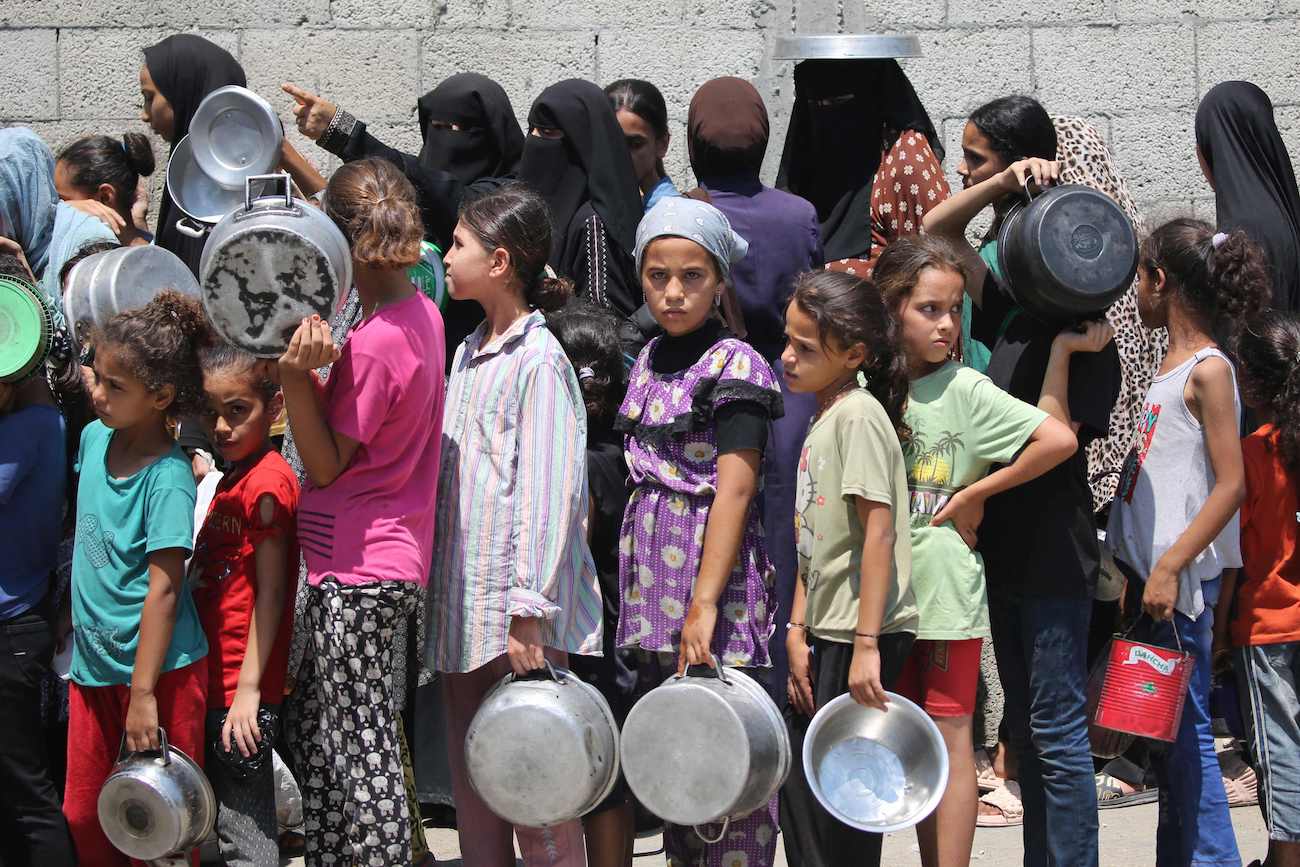 Palestinians gather to receive cooked meals from a food distribution center in the Nuseirat refugee camp in the central Gaza Strip on August 18, 2025. (AFP)