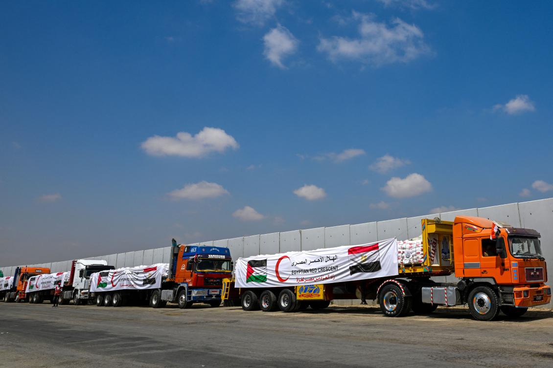 A man (L) walks past trucks loaded with aid for Gaza, waiting on the Egyptian side of the Rafah crossing in Rafah on August 18, 2025. (AFP)