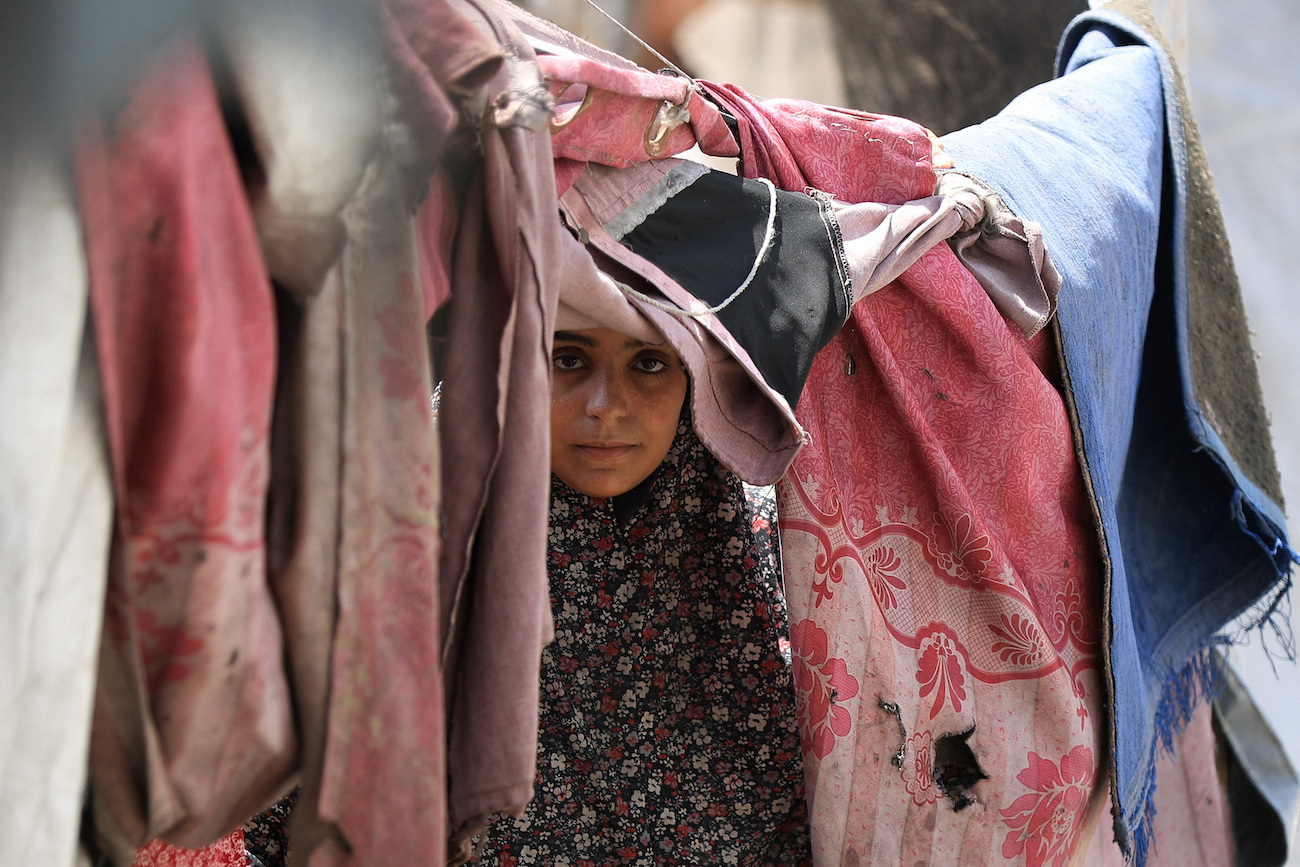 Displaced Palestinian woman shelters in a tent camp as the Israeli military prepares to relocate residents to southern Gaza, August 17, 2025. (Reuters)