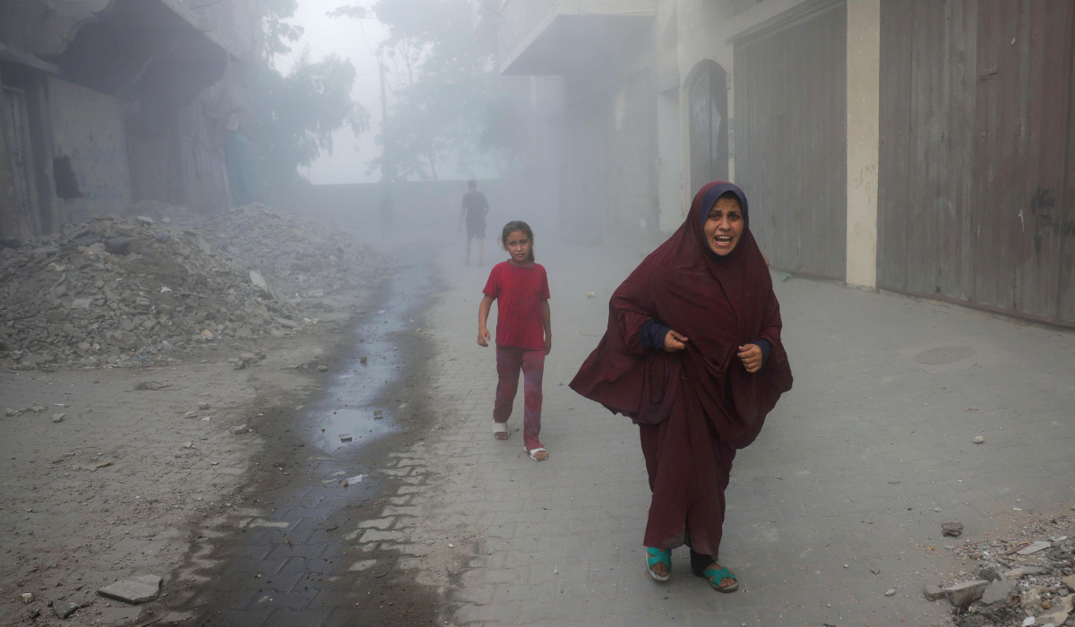 A Palestinian woman and children rush away from the site of Israeli air strikes on a six-storey building in the Saftawi neighborhood west of Jabalia in the northern Gaza Strip on August 19, 2025. (AFP)
