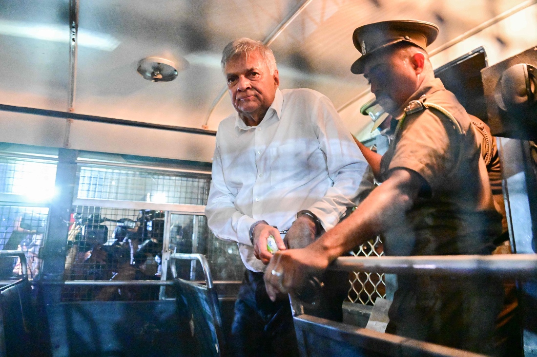Sri Lanka's former president Ranil Wickremesinghe is escorted to his seat in a prison bus in Colombo, Sri Lanka. (AFP)