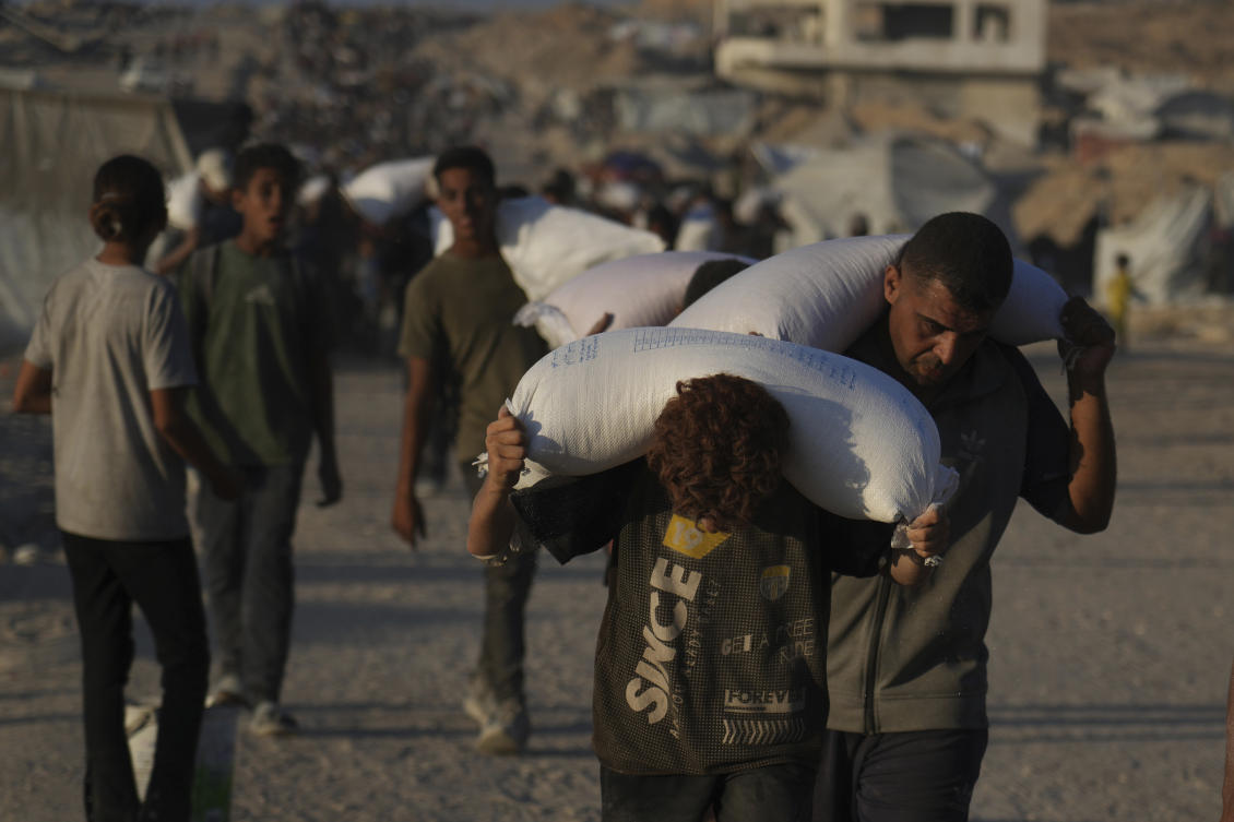 Palestinians carry sacks of flour unloaded from a humanitarian aid convoy that reached Gaza City from the northern Gaza Strip on Sunday. (AP)