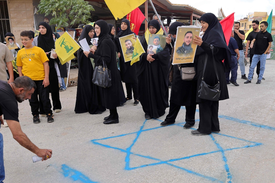 Hezbollah supporters stand above a Star of David graffiti as they demonstrate against the planned visit of US envoy Tom Barrack to south Lebanon. (AFP)