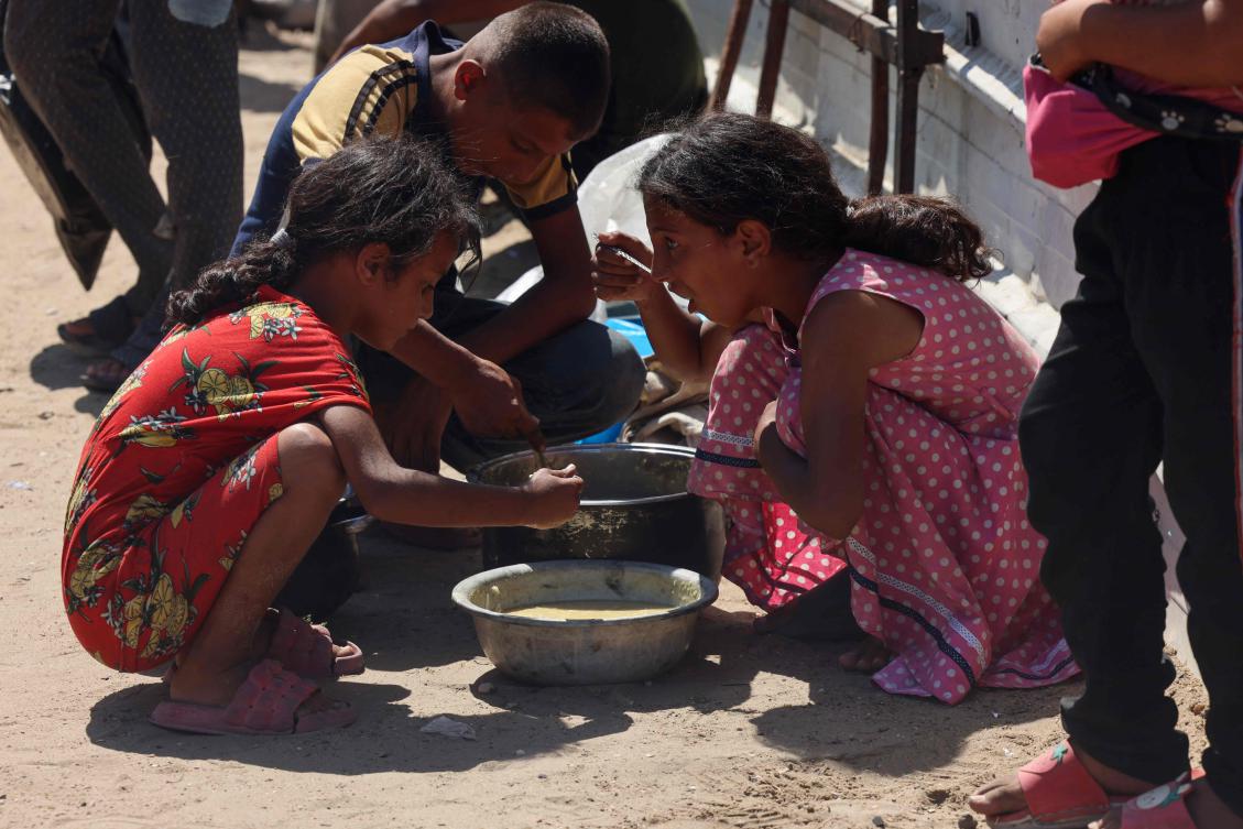 Palestinian children eat cooked rice from a charity kitchen in Khan Yunis in the southern Gaza Strip on Wednesday. (AFP)