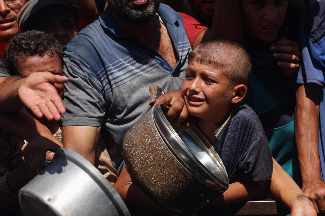 Palestinians struggle to receive food portions from a charity kitchen in Khan Yunis in the southern Gaza Strip on Wednesday. (AFP)