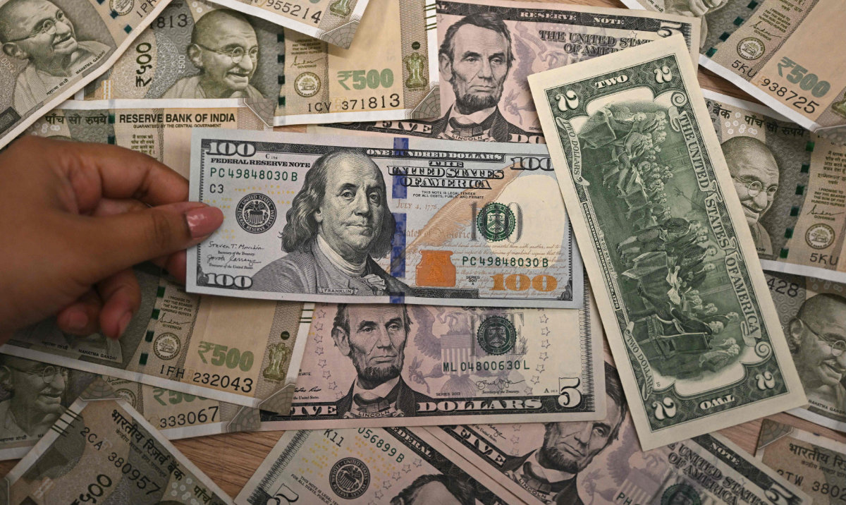 A foreign exchange employee displays Indian rupee and US dollar currency notes at an office in New Delhi on August 26, 2025. US President Donald Trump has threatened to double import duties on India from 25 to 50 percent by August 27, to punish New Delhi for buying oil from Russia, saying the purchases help Moscow fund its invasion of Ukraine. (AFP)