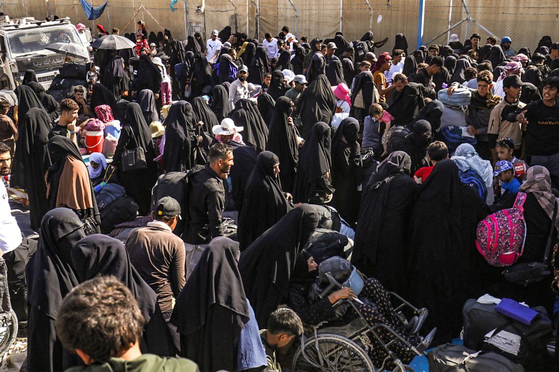 People stand with their belongings as Iraqi nationals prepare to leave the Kurdish-run al-Hol camp in Syria’s northeastern al-Hasakah governorate, ahead of their return to Iraq on August 28, 2025. More than 800 Iraqi nationals left northeast Syria's Al-Hol camp on August 28, an official told AFP, the latest batch to quit the notorious Kurdish-administered camp that also hosts suspected relatives of Islamic State group jihadists. (Photo by Delil SOULEIMAN / AFP)