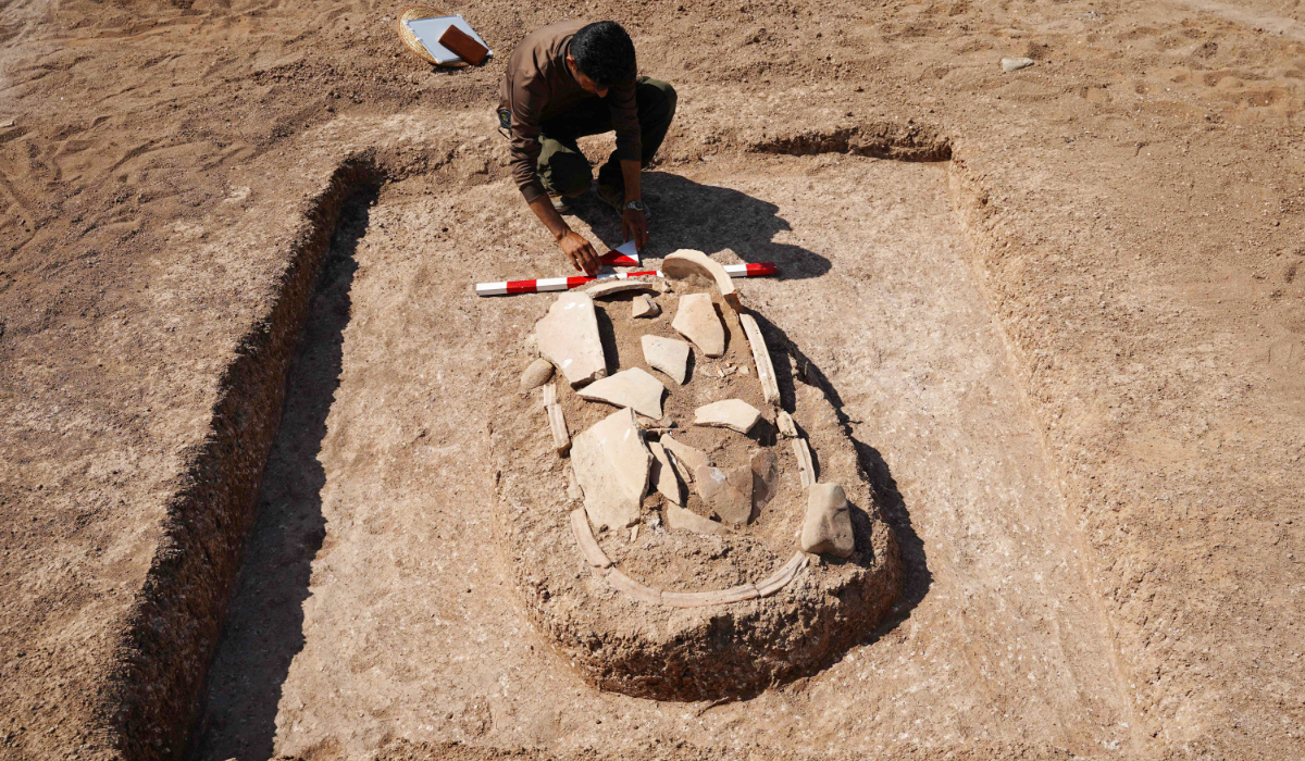 A member of the Antiquities Department works on a grave unearthed on the banks of Mosul Dam on an archaeological site in Iraq’s Dohuk Governorate. (AFP)