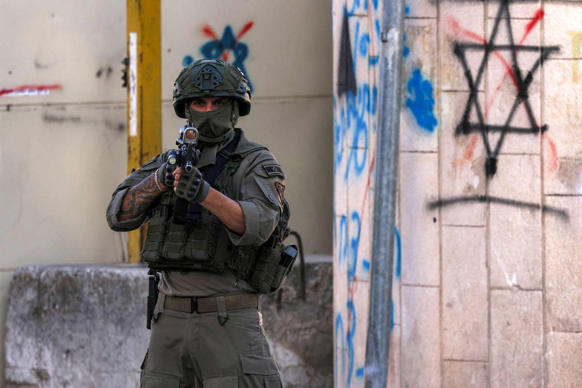 An Israeli soldier stands guard in the old city centre and market of the Palestinian city of Hebron in the occupied West Bank, June 28, 2025. (AFP)