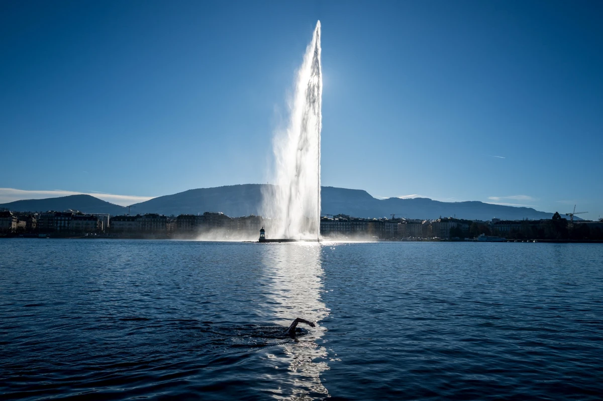 A lake-goer swims in Geneva Lake with the city's landmark fountain in the background. (AFP)