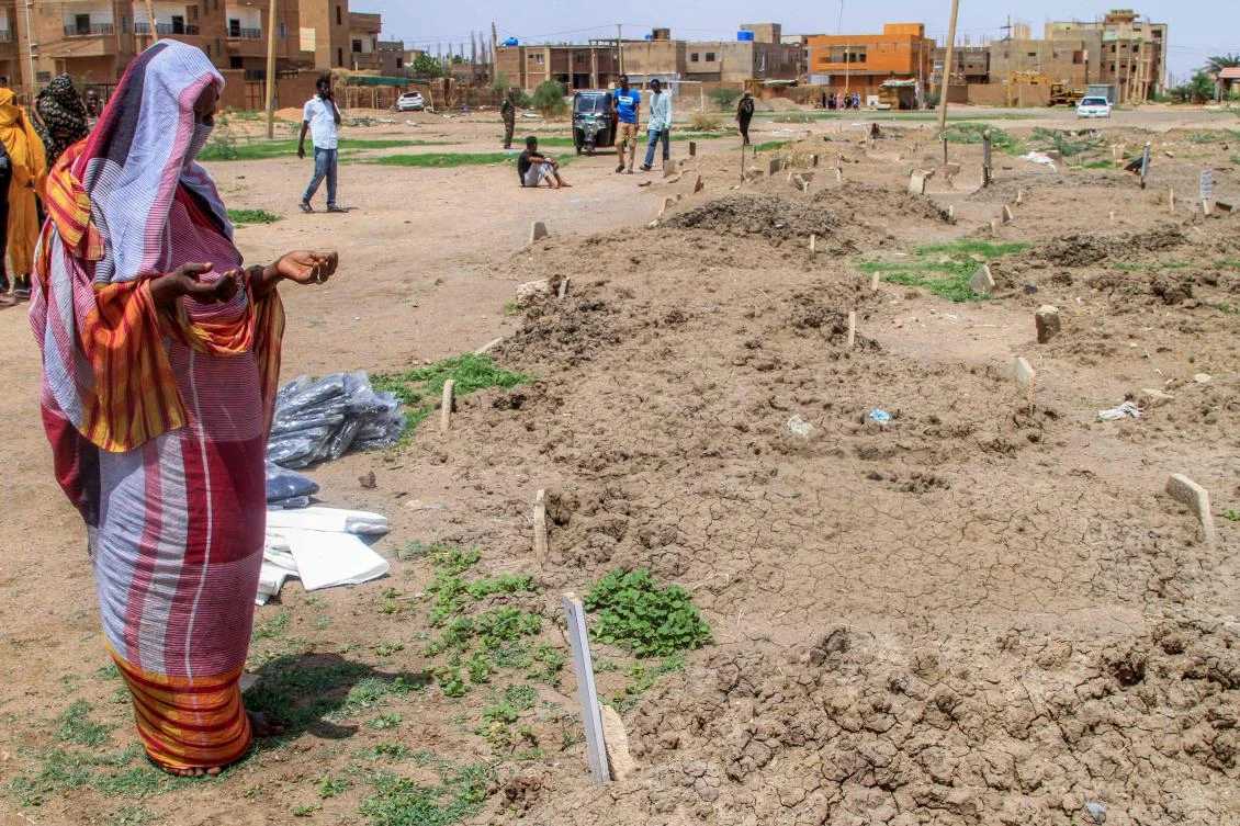 A woman prays by one of the makeshift graves of those buried in Khartoum's southern suburb of al-Azhari on August 2, 2025 when the area was under control of the Rapid Support Forces (RSF) paramilitaries, which will be exhumed for reburial in the local cemetery. (AFP)