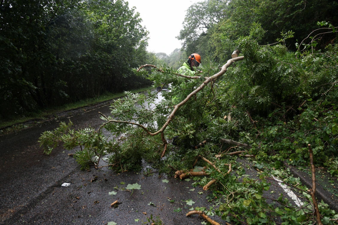 A worker removes a fallen tree blocking a part of the A82 road near Onich, as Storm Floris hits Scotland, Britain, August 4, 2025. (Reuters)