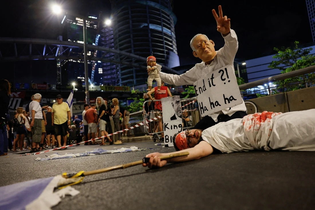 A demonstrator wearing a mask depicting Israeli Prime Minister Benjamin Netanyahu gestures, during a protest in Tel Aviv, Israel. (Reuters)