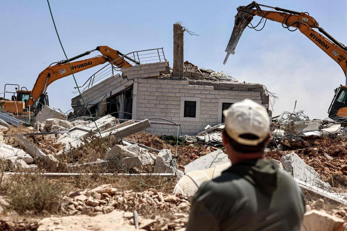 A man watches as Israeli excavators demolish a building in the village of Judeira, south of Ramallah in the occupied West Bank on August 4, 2025. (AFP)