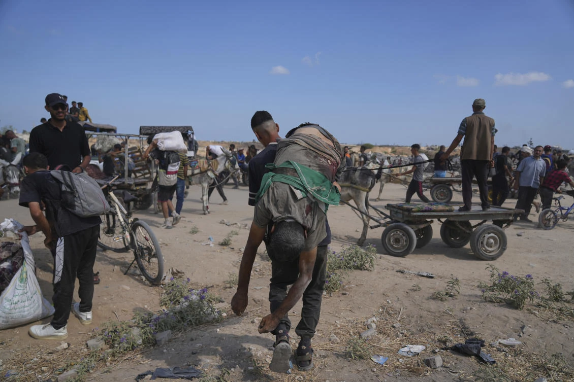 A Palestinian carries the body of a man killed while trying to receive aid near a distribution center operated by the US-backed Gaza Humanitarian Foundation in Netzarim, in the Gaza Strip, Monday, Aug. 4, 2025. (AP)