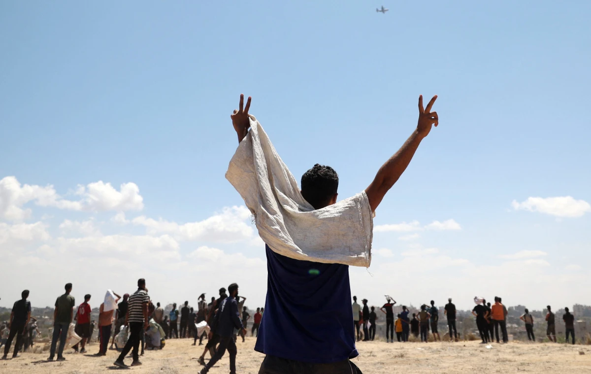 A man reacts as a plane carrying humanitarian aid flies over Nuseirat in the central Gaza Strip during a aid airdrop mission above the Israel-besieged Palestinian territory on August 5, 2025. (AFP)