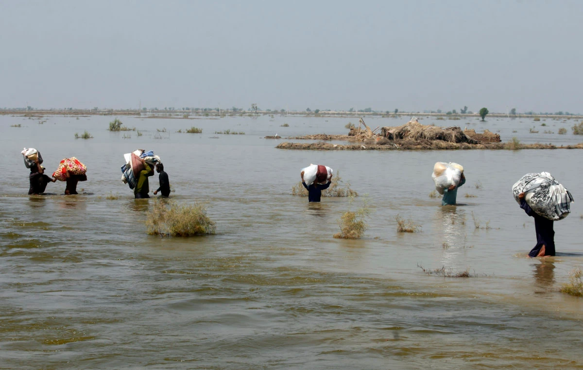 Victims of heavy flooding from monsoon rains carry relief aid through floodwater in the Qambar Shahdadkot district of Sindh Province, Pakistan, on Sept. 9, 2022. (AP Photo/File)