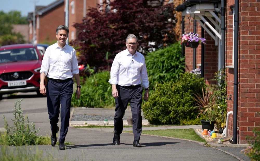 Keir Starmer, right, and Ed Miliband visit the house of a local resident as the government announces changes to the Warm Homes Discount, Rocester, England, June 19, 2025. (Reuters)