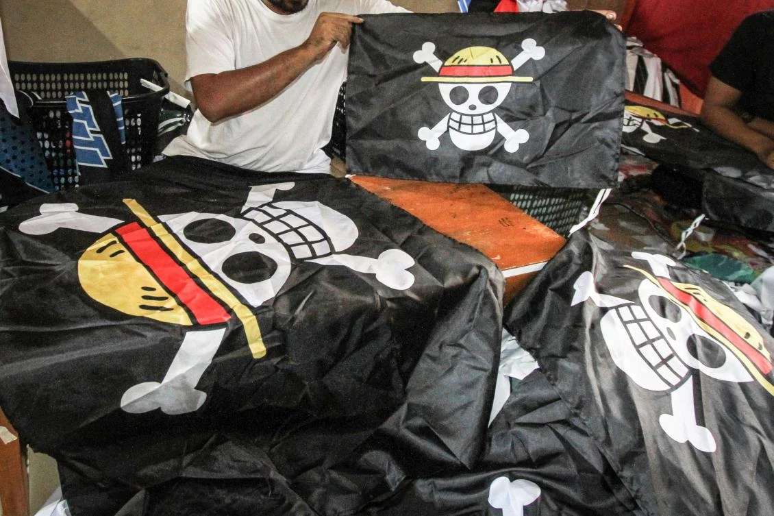 A worker holds a replica of the pirate flag from Japanese anime One Piece at a T-shirt workshop in Karanganyar, Central Java, on Aug. 6, 2025. (AFP)