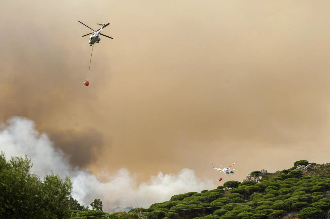 Firefighting helicopters drop water to extinguish a blaze in Torre de la La Peaa near the southern Spanish tourist town of Tarifa. (Europa Press via AP)