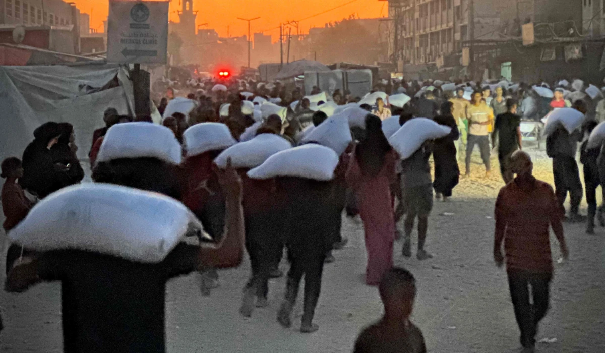 Men walk carrying sacks of flour that were taken from a raided truck carry sacks of flour after raiding a truck that was carrying foodstuffs, in Khan Yunis in the southern Gaza Strip on July 22, 2025. (AFP)