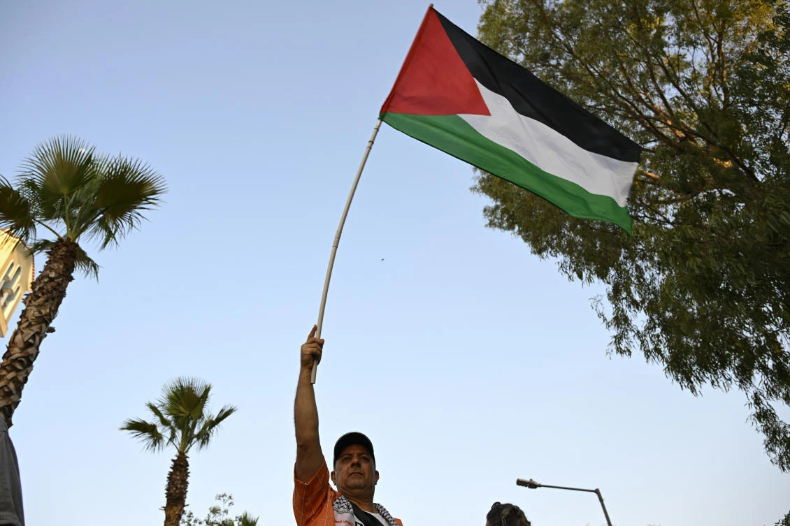 A protester waves a Palestinian flag during a rally to protest the arrival of a cruise ship with Israelis, in Piraeus port, Greece, Aug. 14, 2025. (AP)