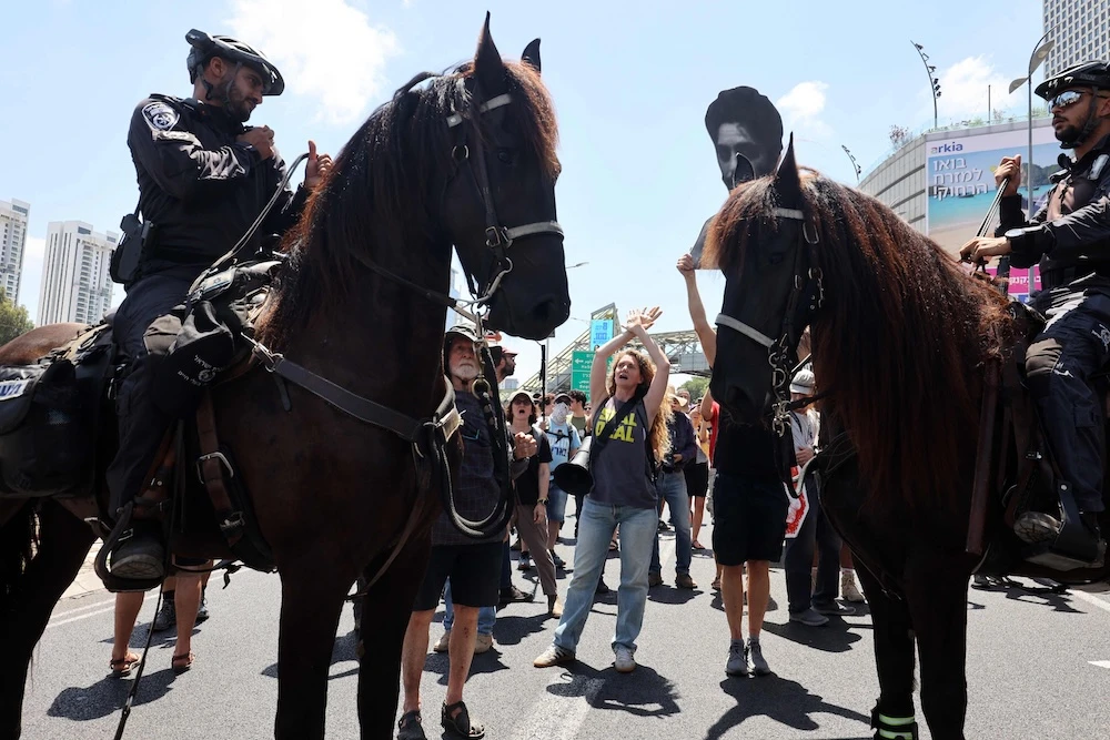 A demonstrator shouts slogans in front of mounted policemen during an anti-government protest in Tel Aviv on Aug. 17, 2025. (AFP)