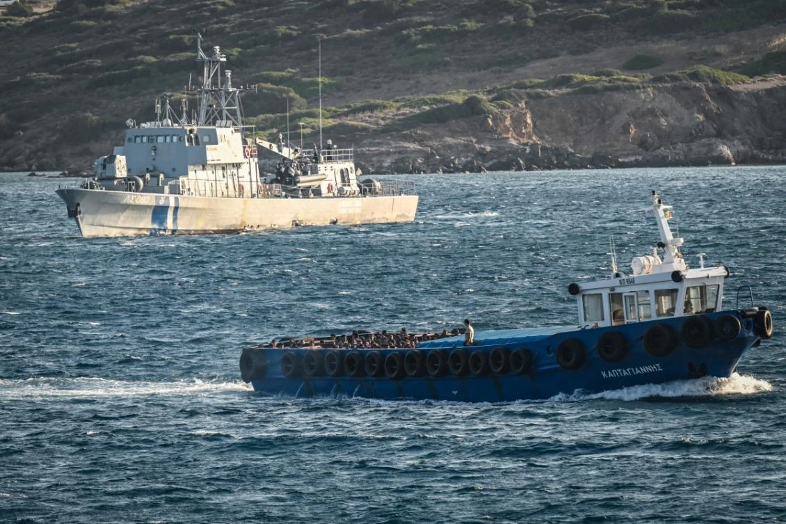 Migrants stand on board a boat after disembarking from a cargo ship before being tranferred, in the port of Lavrio, south of Athens, on July 10, 2025. (AFP)