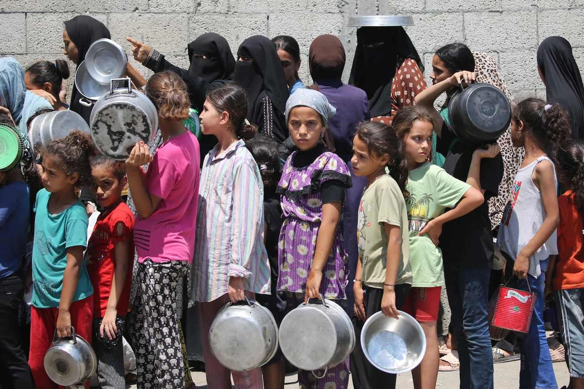 Palestinians gather to receive cooked meals from a food distribution center in the Nuseirat refugee camp in the central Gaza Strip on August 18, 2025. (AFP)