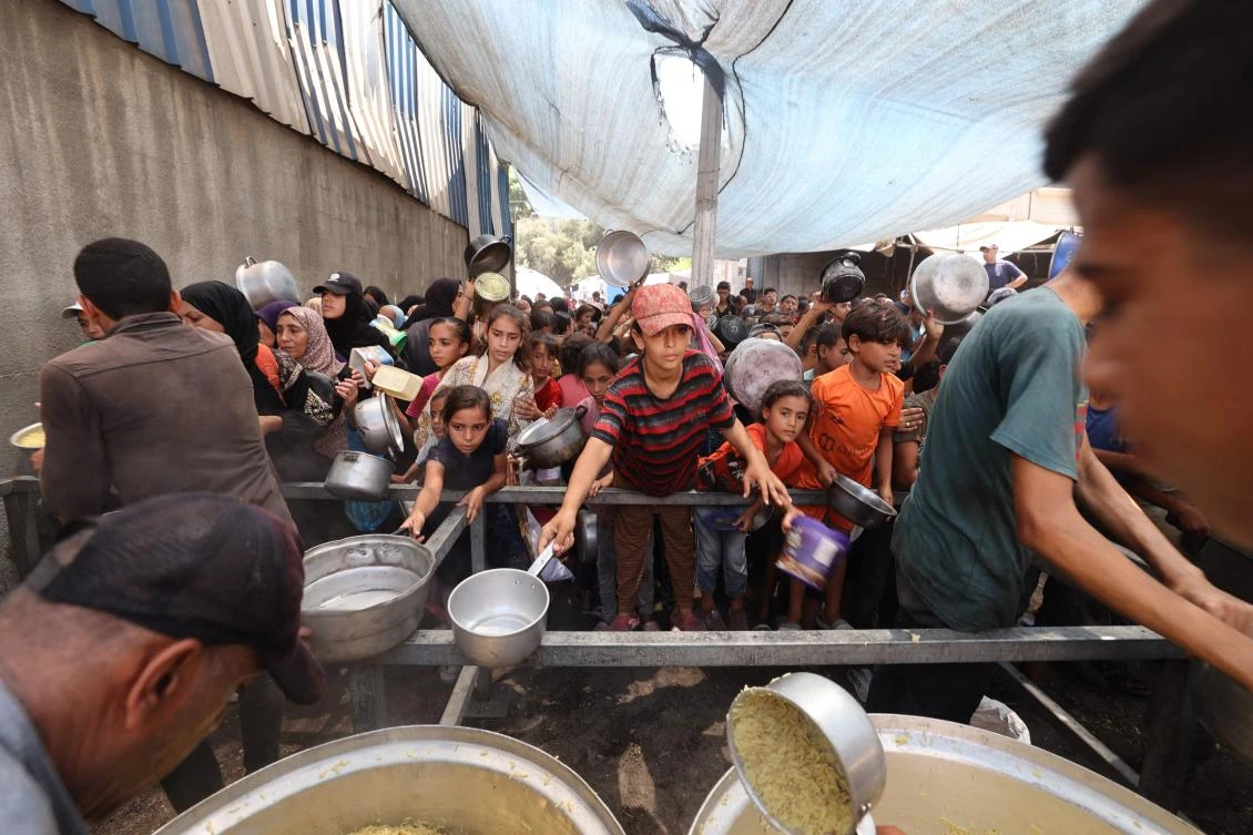 Above, Palestinians gather to receive cooked meals from a food distribution center in the Nuseirat refugee camp in the central Gaza Strip on Aug. 18, 2025. A record 383 aid workers were killed in global hotspots in 2024, nearly half of them in Gaza. (AFP)