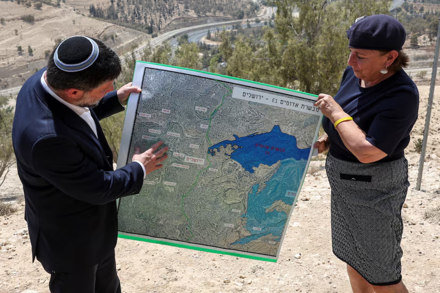 Israeli Finance Minister Bezalel Smotrich and a woman hold a map that shows the E1 settlement scheme (File/Reuters)