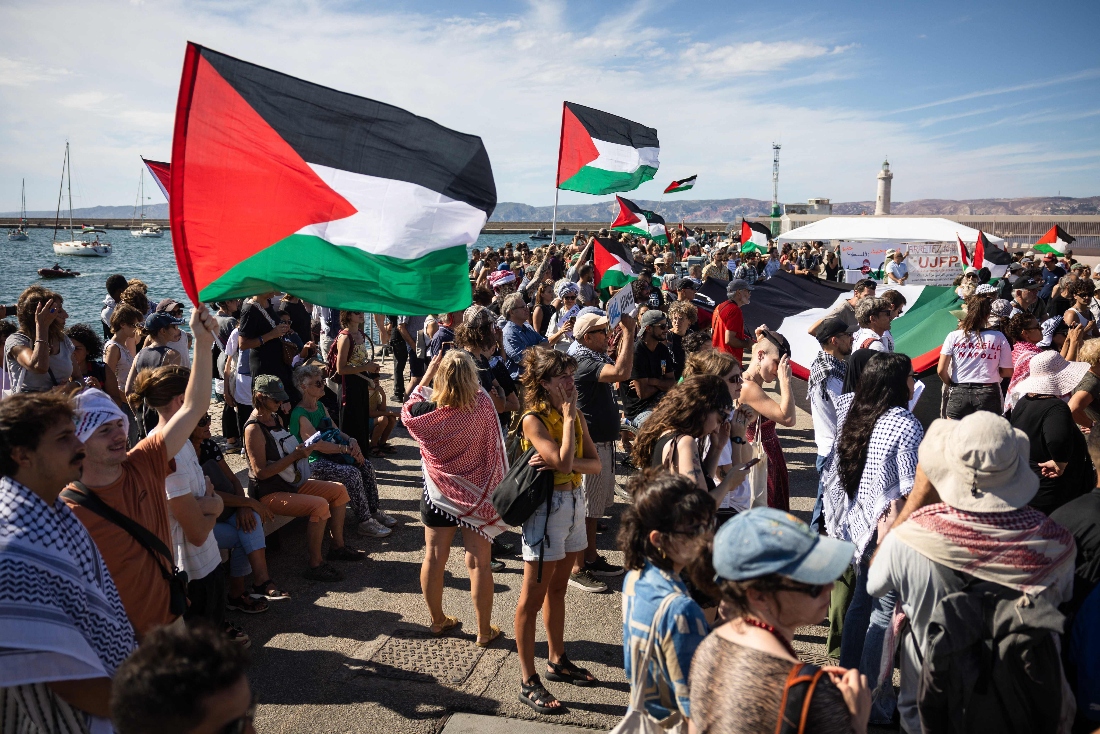 People wave Palestinian flags as they gather in Marseille, France harbour in support of a flotilla bound for Gaza carrying humanitarian aid. (AFP)