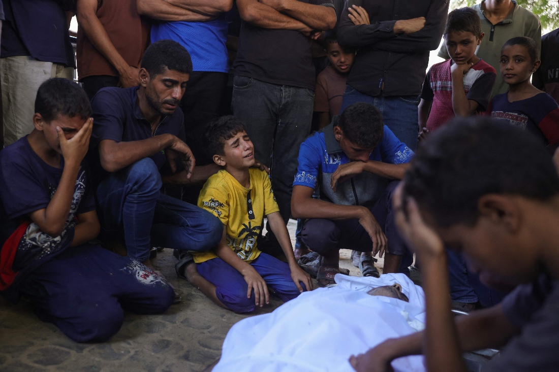 Palestinians mourn by the shrouded body of a relative killed in Israeli strikes on Gaza City. (AFP)