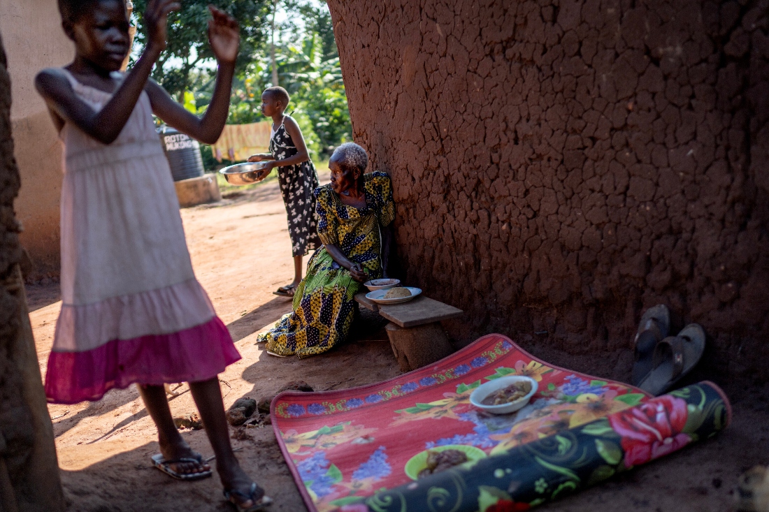 A grandmother sits with her granddaughters in a home they share at Magogo, Uganda. (AP)