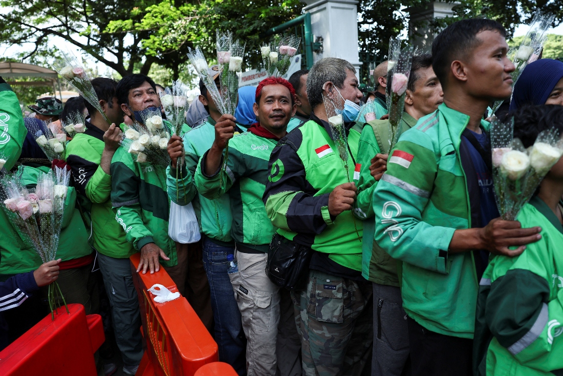 Ride hailing motorbike drivers hold flowers to distribute it to people including security officers and military, during a rally calling for peace in Indonesia. (Reuters)