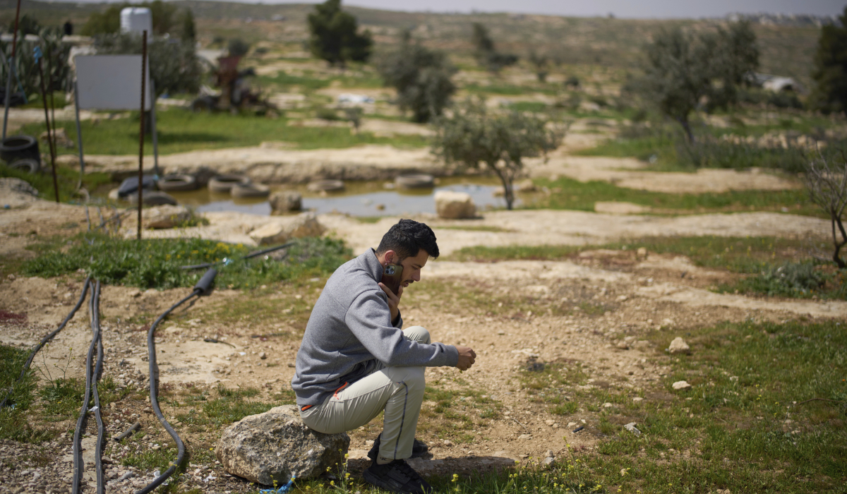 Basel Adra, one of the directors of the Oscar winner documentary "No Other Land", speaks on the phone as he sits in an area near the house of Palestinian co-director Hamdan Ballal, in Susiya in Masafer Yatta, south Hebron hills, March 25, 2025. (AP)