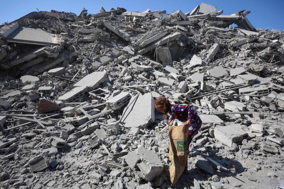 A Palestinian girl searches the rubble of Al-Ghafari tower after its destruction by Israeli airstrikes in Gaza City on Monday. (AFP)