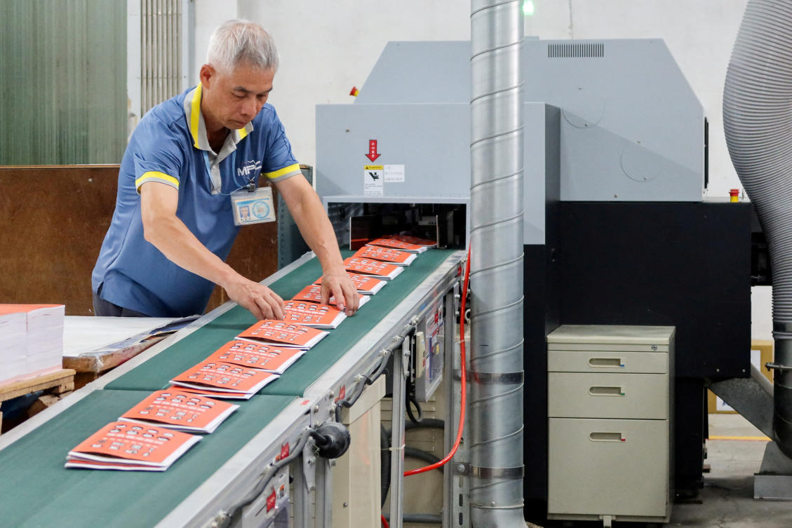 A worker handles copies of Taiwan’s updated civil defense handbook at a printing house in Taoyuan. The government wants people to put a copy of the handbook in grab bags containing emergency supplies stored in an easily accessible location. (Reuters)