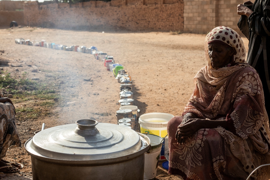 A Sudanese woman from a community kitchen, run by local volunteers, prepares meals for people who are affected by conflict and extreme hunger and are out of reach of international aid efforts, as empty pots are seen lined up to receive food, in Omdurman, Sudan. (Reuters)