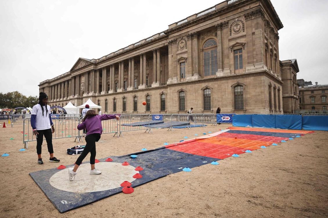 A girl performs a shot put in front of the Louvre Museum during Sports Day in Paris on Sept. 14, 2025. (AFP)