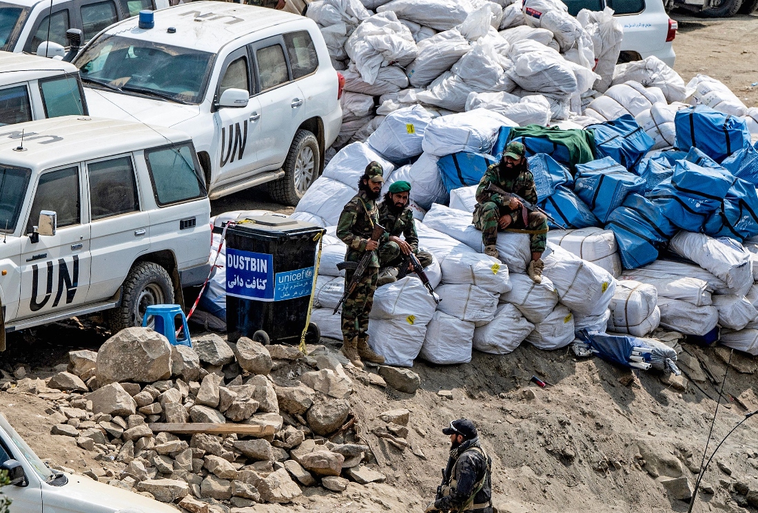 Taliban security personnel sit over sacks of relief aid kept beside official vehicles of the United Nations in the aftermath of an earthquake in Afghanistan. (AFP)