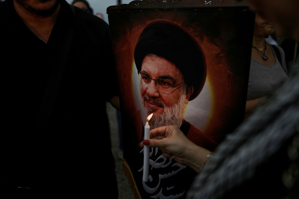 A supporter of Lebanon’s Hezbollah group holds a candle next to a poster of slain Hezbollah leader Hassan Nasrallah during a gathering in Beirut, Lebanon, Wednesday, Sept. 17, 2025. (AP Photo)