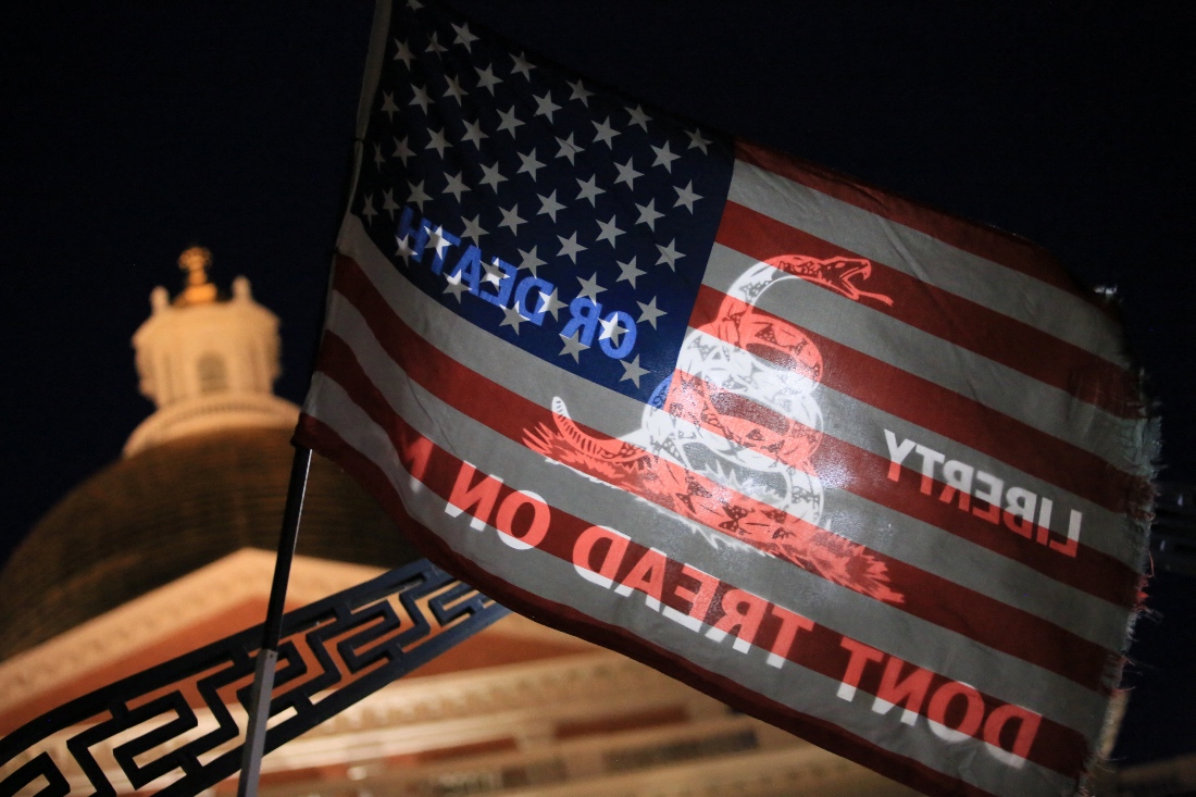 A flag with the U.S. flag on one side, and a variation of the "Don't Tread on Me" flag on the other, is held in front of the State House during a prayer vigil for Charlie Kirk in Boston, US.
