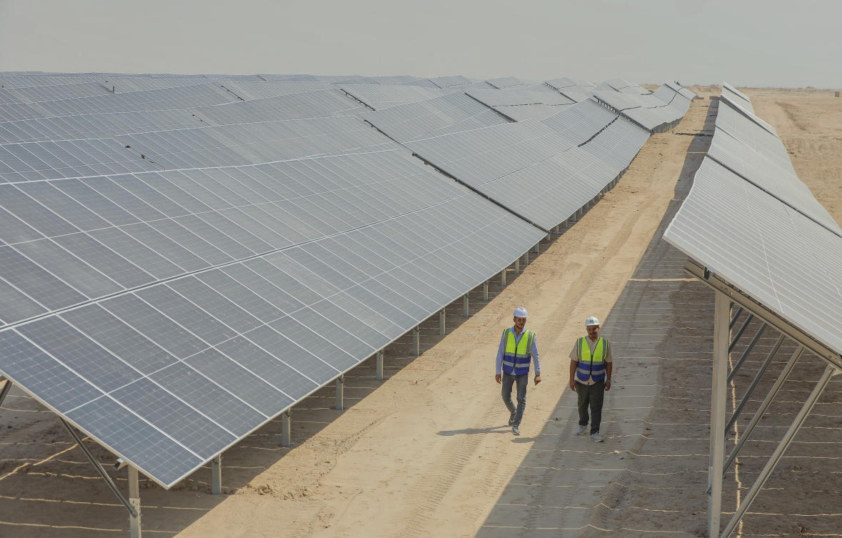 Workers walk between solar panels at a newly opened industrial-scale solar power plant in Karbala, Iraq, Wednesday, Sept. 17, 2025. (AP Photo/Anmar Khalil)