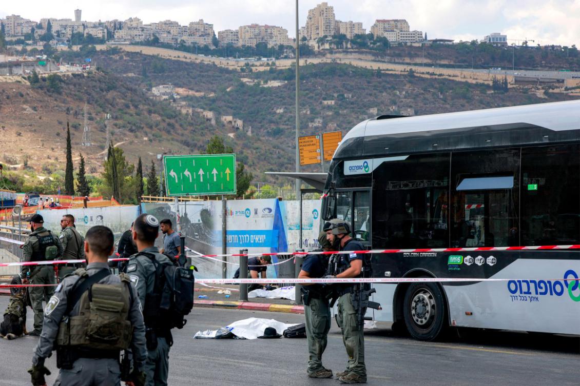 Israeli security forces gather by a body next to a bus at the scene of a shooting at the Ramot Road junction in Israeli-annexed east Jerusalem. (File/AFP)