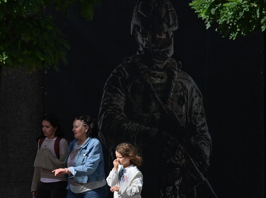 A family walks past a placard depicting Ukrainian serviceman in Kyiv, Ukraine. (AFP)