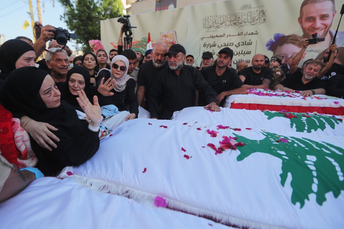 Amani Bazzi mourns over the coffins of her husband Shadi Charara and three children during their funeral procession in Bint Jbeil, southern Lebanon. (AP)