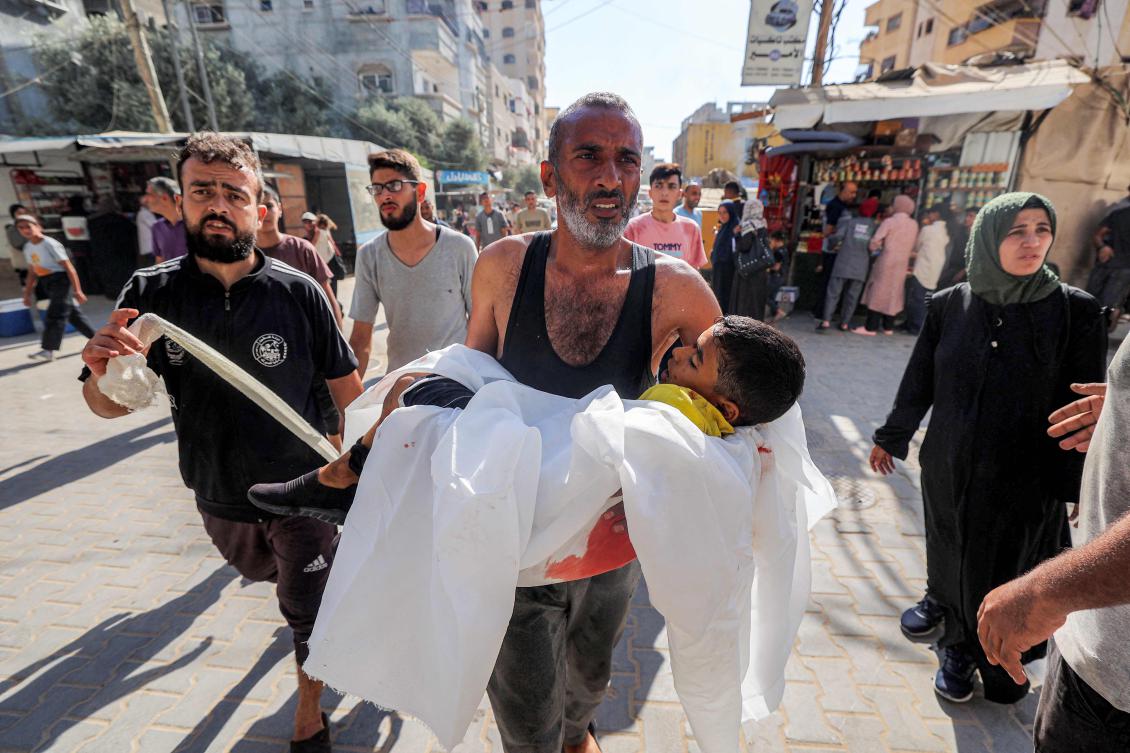 A man reacts as he carries the body of a child killed by reported Israeli bombardment on al-Bureij, outside al-Awda Hospital in Nuseirat in the central Gaza Strip on September 21, 2025. (Eyad Baba, AFP)